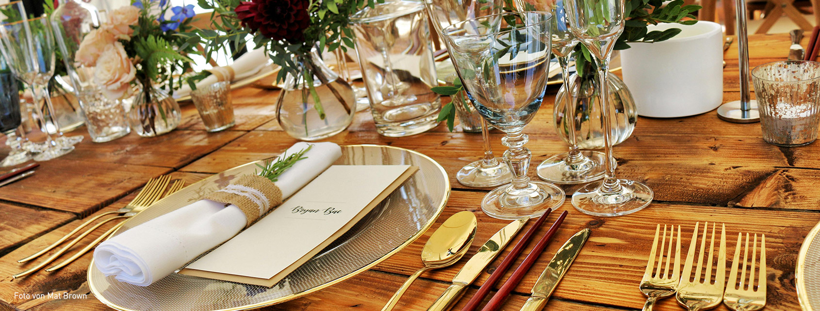 ein festlich gedeckter Holztisch für mehrere Gänge