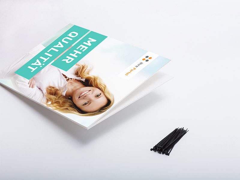 Die Abbildung zeigt ein leicht aufgeklapptes Doppel-Hohlkammerplakat. Daneben liegen einige Kabelbinder zur Befestigung.