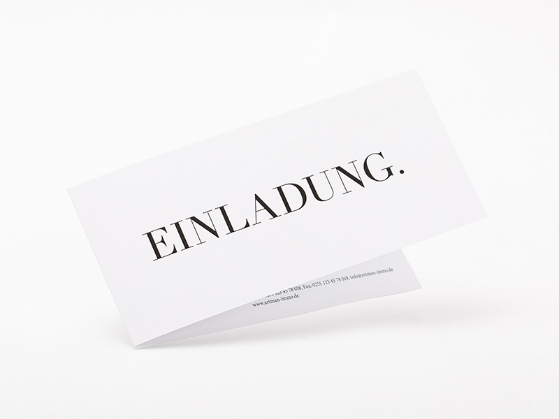 Eine schräg gestellte, leicht aufgeklappte Grußkarte im schmalen Querformat und der Aufschrift Einladung.
