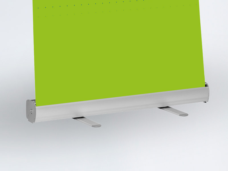 Eine silberfarbene einfache Kassette aus der eine Roll Up Bahn im Anschnitt gezeigt wird. Letztere ist grün bedruckt.